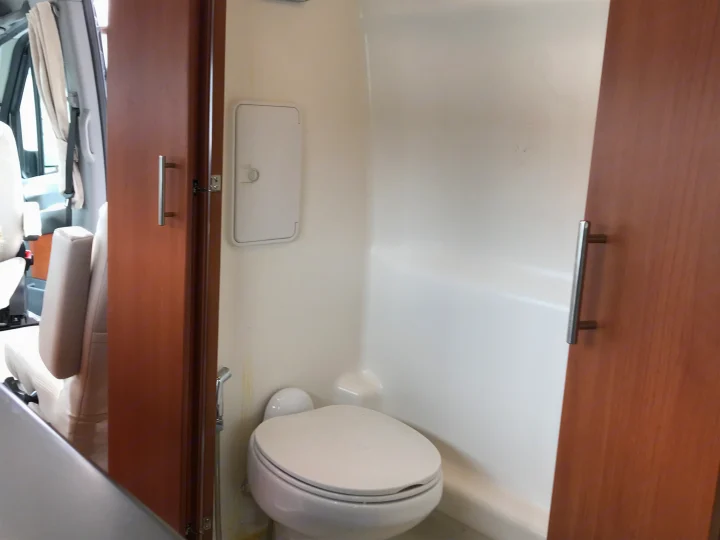 This RV rental features a compact bathroom with a toilet and wet-bath style shower, adjacent to the front seats.. Winnebago Era 2014