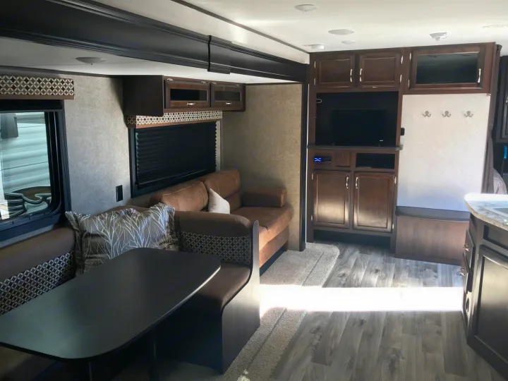 Cozy RV rental living area featuring a dining booth, comfortable sofa, entertainment center with TV, and ample storage.. Jayco JAY FLIGHT SLX 287 BHS 2018