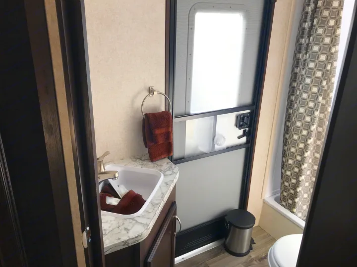 RV rental interior: A compact bathroom with a sink, brown towels, a main entry door, plus a toilet and shower.. Jayco JAY FLIGHT SLX 287 BHS 2018