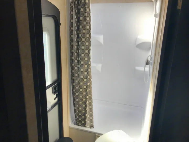 Clean RV rental bathroom featuring a white shower stall with a shower curtain and a partial view of the toilet.. Jayco JAY FLIGHT SLX 287 BHS 2018