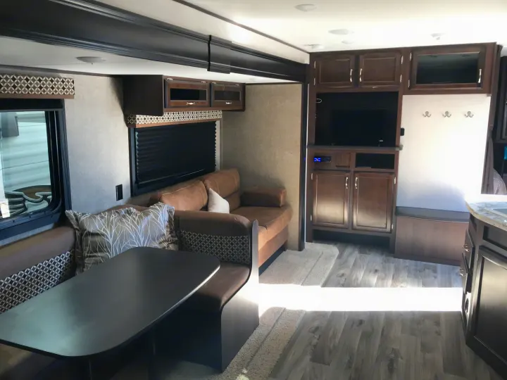View inside an rv rental, showcasing its dinette, sofa, and entertainment area with dark wood and patterned accents.. Jayco JAY FLIGHT SLX 287 BHS 2018