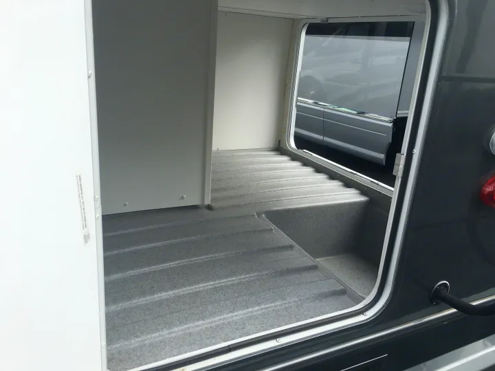 Open RV rental storage compartment with multi-level carpeted floor, ready for gear.. ForestRiver Sunseeker 2018