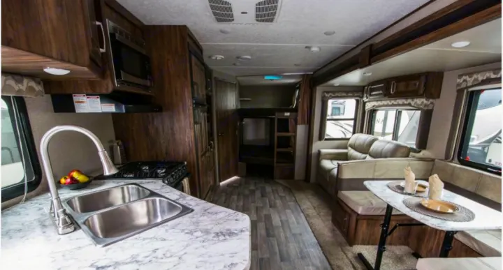 This RV rental offers a spacious interior with a full kitchen, dining area, cozy sofa, and bunk beds for family comfort.. Keystone Cougar Half-Ton 2018