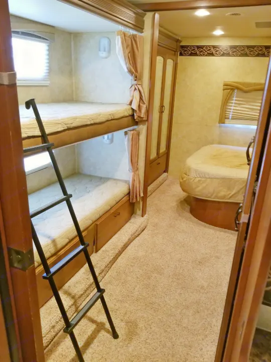RV rental interior features bunk beds with a ladder, a cozy corner bed, storage, and carpeted flooring.. Jayco Greyhawk 2011
