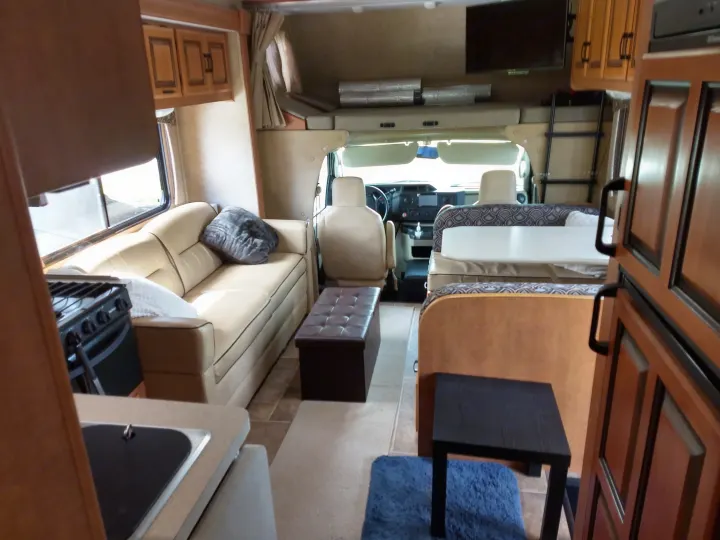 Step inside this comfortable RV rental, showcasing its living area, kitchen, and overhead sleeping bunk.. Forest River Sunseeker 2013