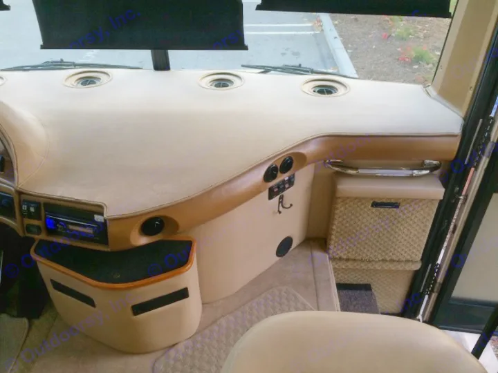 Experience an RV rental: Spacious, clean beige dashboard, radio, grab handle, and storage in this motorhome cockpit.. Fleetwood Discovery 2005
