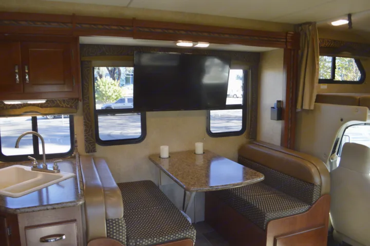 RV rental interior: compact kitchen, dinette with TV, and front cab view. Ideal for travel and camping adventures.. Thor Motor Coach Chateau 29G 2016