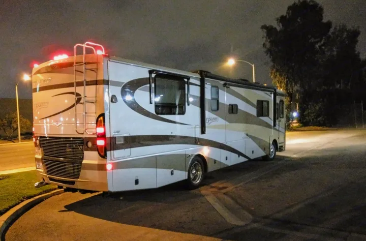 This Fleetwood Discovery motorhome, perfect for an RV rental adventure, is parked at night under streetlights.. Fleetwood Discovery 2005