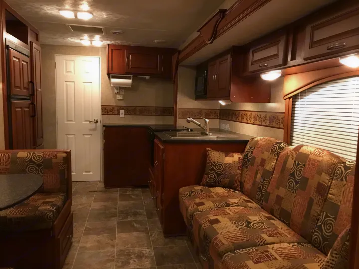 Cozy RV rental interior featuring a kitchen, dinette, and comfortable sofa, perfect for your next road trip.. Forest River Wildwood 2011