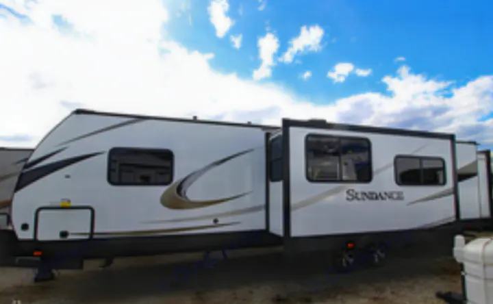 A white Sundance travel trailer, or RV, with an extended side section (slide-out) for more space, available for RV rental.. Heartland Sundance 2019
