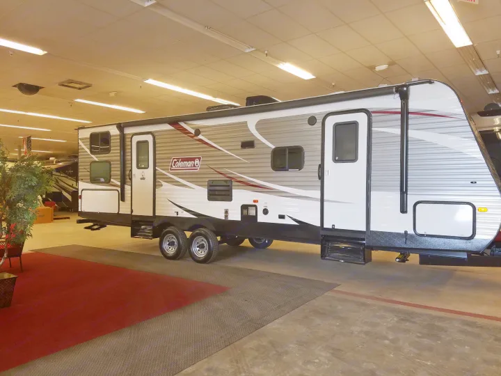 A modern Coleman travel trailer, a type of RV often used for rv rental, showcased indoors in a dealership showroom.. Coleman 285bh 2017