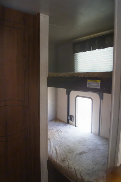 Inside an RV rental: upper & lower bunk beds with a window & small access door for cozy, compact living.. Heartland Other 2018