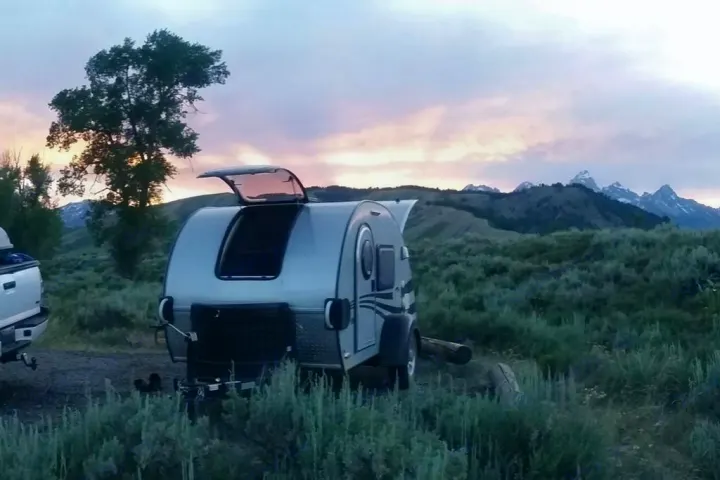 This RV rental, a teardrop camper, is parked for camping at sunset, revealing snow-capped mountains in the background.. Little Guy Silver Shadow 2016