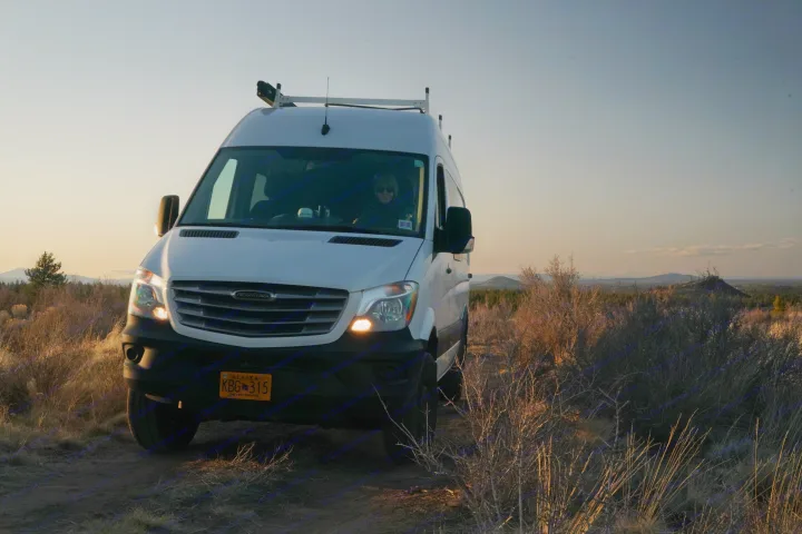 White Freightliner camper van, ideal for rv rental, on a dirt path at golden hour. Adventure awaits!. Freightliner Sprinter 2016