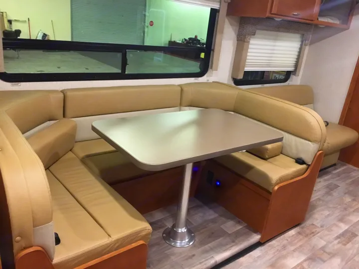 Spacious U-shaped dinette in an RV rental, featuring comfortable seating, a table, and windows to the outside.. Winnebago Minnie Winnie 2017