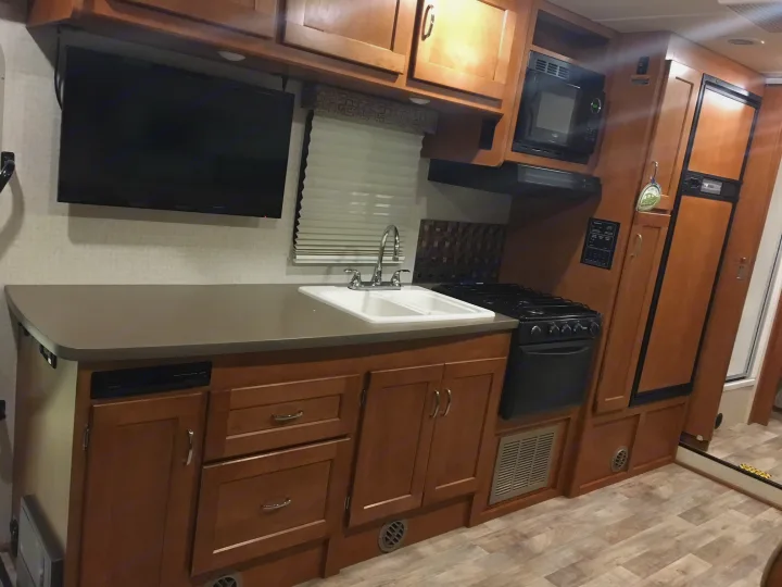 RV rental interior: a fully equipped kitchen with sink, stove, microwave, refrigerator, and wall-mounted TV. Ideal for travel.. Winnebago Minnie Winnie 2017