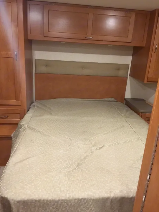 Cozy RV rental bedroom with comfortable bed and built-in wooden cabinetry for storage.. Winnebago Minnie Winnie 2017