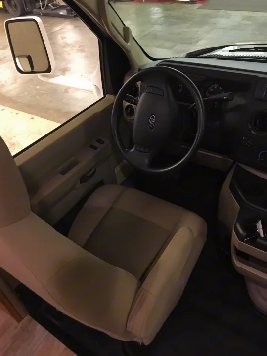 Inside an rv rental: the driver's cockpit featuring a Ford steering wheel, dashboard, and beige seats.. Winnebago Minnie Winnie 2017