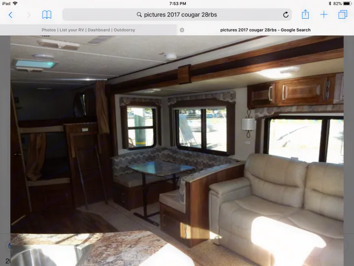Spacious RV rental interior featuring bunk beds, U-shaped dinette, and a comfy sofa. Includes a kitchen area, ideal for travel.. Keystone Cougar Half-Ton 2017