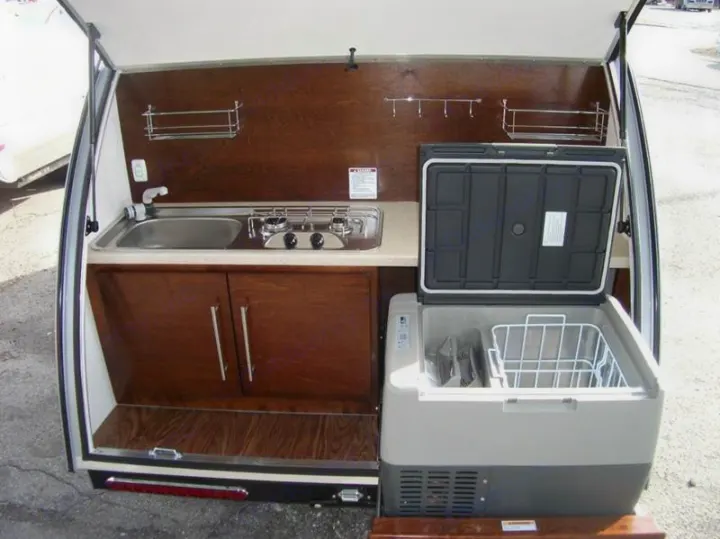 This RV rental features a compact outdoor kitchen with sink, stove, cabinets, and a portable fridge/cooler.. Little Guy Silver Shadow 2016