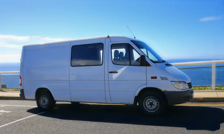 White campervan RV rental parked with an ocean view on a sunny day, ready for adventure.. Mercedes-Benz Sprinter 2005