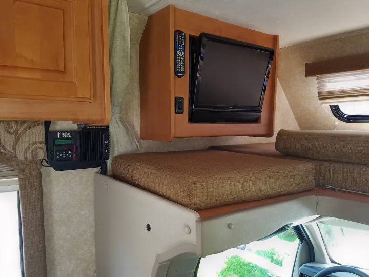 Inside an RV rental: a mounted TV, solar charge controller, and cozy bed over the cab.. Four Winds Chateau Sport 2008