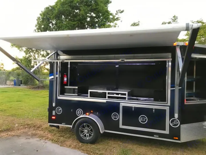 Dark blue custom mobile display trailer with screens, awning, and equipment. A versatile RV rental option for events.. GameDay Mobile Marketer GameDay Mobile Marketer 2020