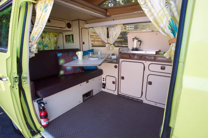 Inside a vibrant lime green Westfalia camper van, perfect for RV rental adventures. Features kitchen, dining, and seating.. Volkswagen westfalia 1984
