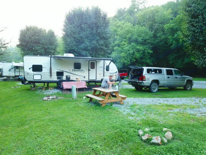 Relaxing at a peaceful campground with an RV rental, truck, and picnic setup amidst lush greenery.. Shasta Oasis 2013