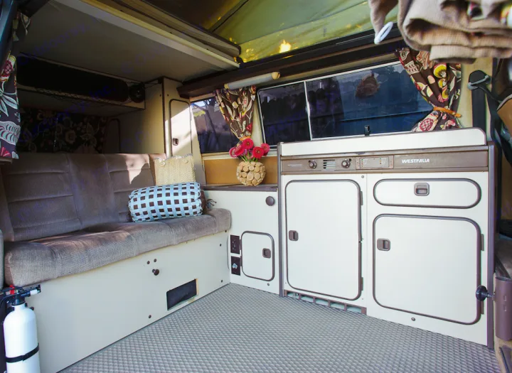 Cozy RV rental interior with Westfalia kitchen, comfy seating, and pop-top roof. Ideal for your next mobile adventure.. Volkswagen Westfalia 1986
