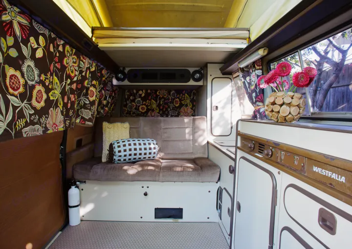 Cozy Westfalia RV rental interior: sofa, kitchen, pop-top, and floral curtains for your adventure.. Volkswagen Westfalia 1986
