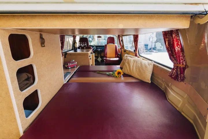 This RV rental offers a cozy interior with a spacious bed, built-in storage, and a small counter for drinks.. Volkswagen Westfalia 1978