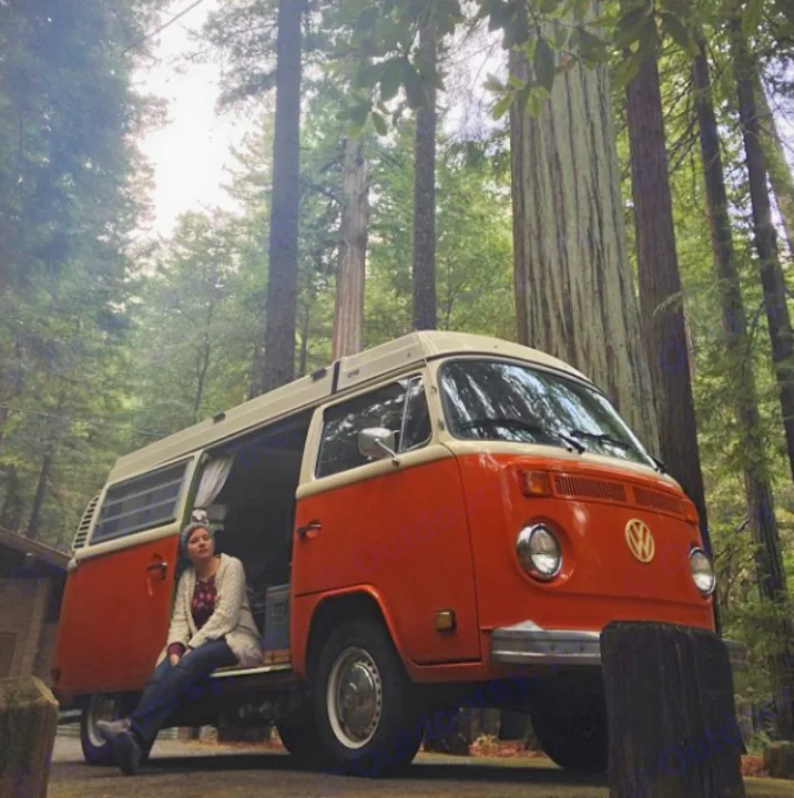 Woman unwinds in a vintage orange VW bus.. Volkswagen westfalia 1979