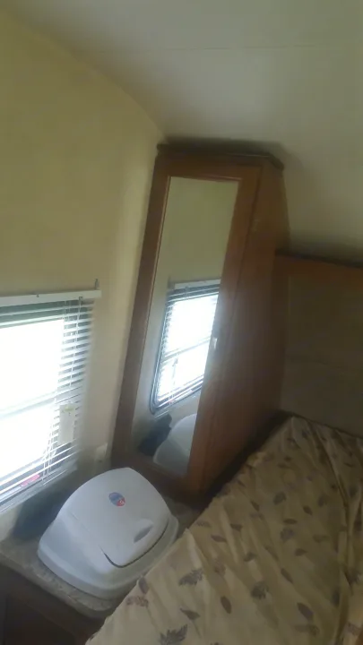 View inside an RV rental bedroom showing a bed, mirrored cabinet, and window with blinds.. Forest River Salem Cruise Lite 2017