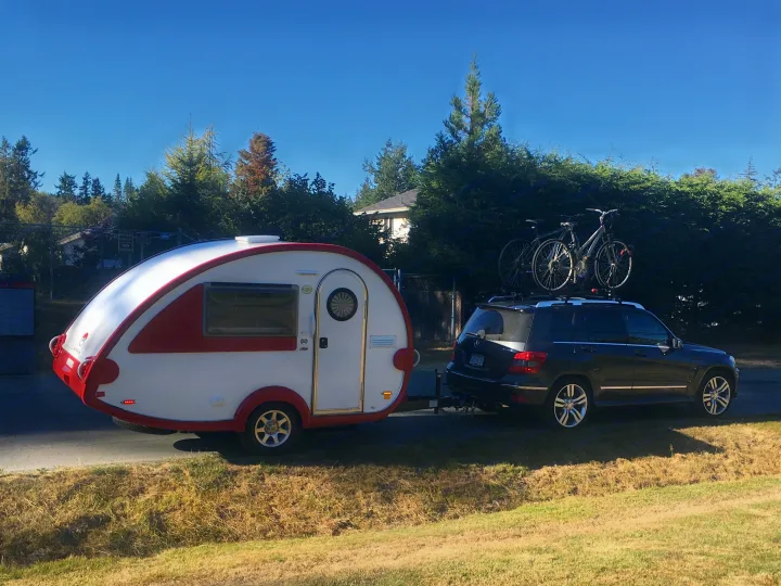 White & red teardrop camper hitched to SUV with bikes, perfect for your next rv rental adventure or camping trip.. T@B Q Floorplan Maxx Package 2016