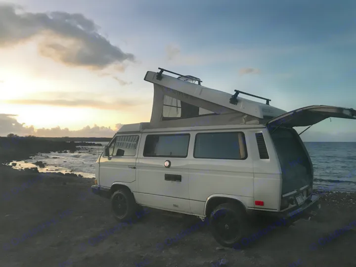 White VW Westfalia camper van by the ocean at sunset, pop-top and rear hatch open. Your perfect rv rental adventure.. VW Westfalia 1990
