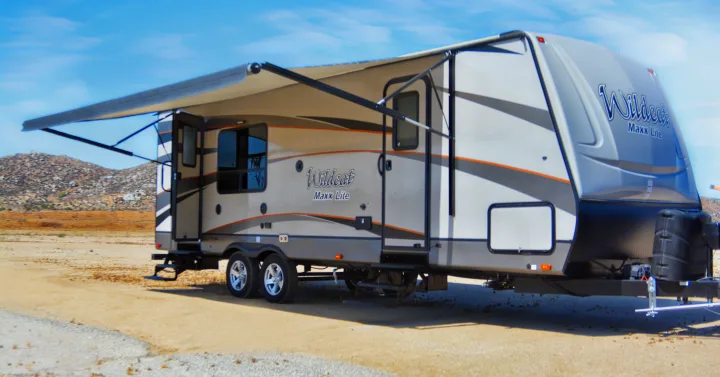Wildcat Maxx Lite travel trailer RV rental, with an extended awning, parked in a sunny, dry outdoor setting.. Forest River Wildcat Maxx Lite 2018