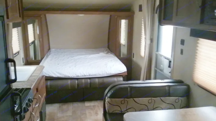 RV rental interior: bedroom with bed, kitchen with sink & stove, and a dinette. A cozy, functional living space for travel.. Gulfstream 248BH 2018
