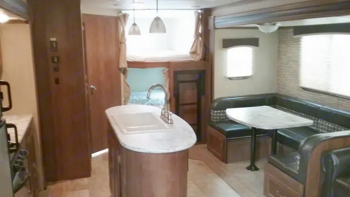 Spacious RV rental interior featuring a kitchen island, dinette with booth seating, and bunk beds. A comfortable camper for travel.. Gulfstream 288ISL 2019