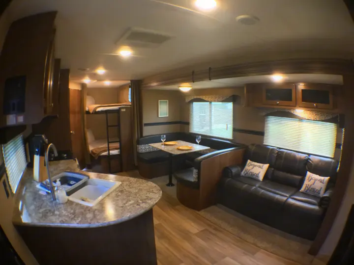 Spacious RV rental interior with kitchen, dining, and living areas, plus bunk beds. Ideal for your next trip.. Dutchmen Aspen Trail 2018
