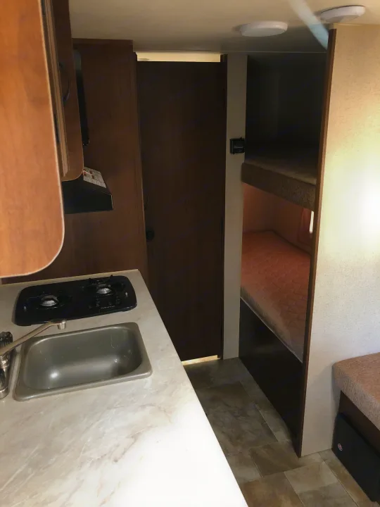 RV rental: Compact interior view with kitchen counter (sink, stove), a closed door, and comfortable bunk beds for guests.. Jayco Jay Flight SLX 2015