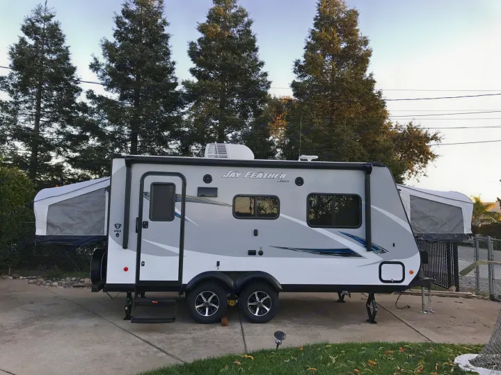 Jay Feather travel trailer, a spacious RV rental parked in a driveway with its pop-outs open.. Jayco Jay Feather 2017