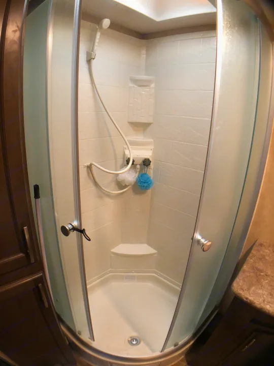 Clean, compact shower in an RV rental, featuring glass doors, a handheld showerhead, and bath accessories.. Forest River Evo 2017