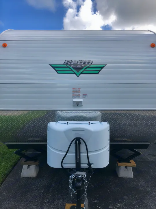 White Retro Riverside RV rental's front, highlighting the propane tank cover & stabilizing jacks for easy setup.. Riverside Rv 189R Retro 2018