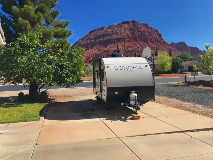 Sonoma RV rental parked on sunny driveway with large red mountain backdrop. Ideal for outdoor adventures.. Forest River Forester 2017