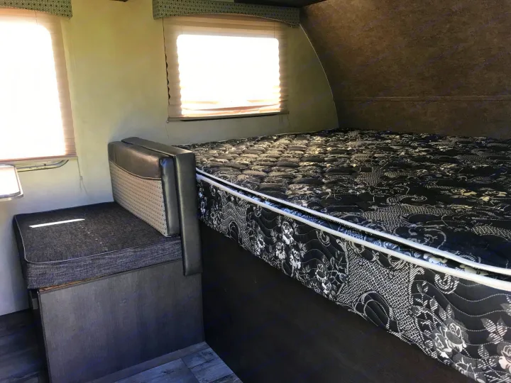 RV rental interior: View of a compact sleeping area featuring a patterned bed, bench seat, and bright windows.. Forest River Forester 2017