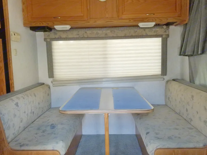 Dining table that folds down into a bed for sleeping, room for 2. Storage above and below this area.. Winnebego Mighty Minnie Winnie 2003