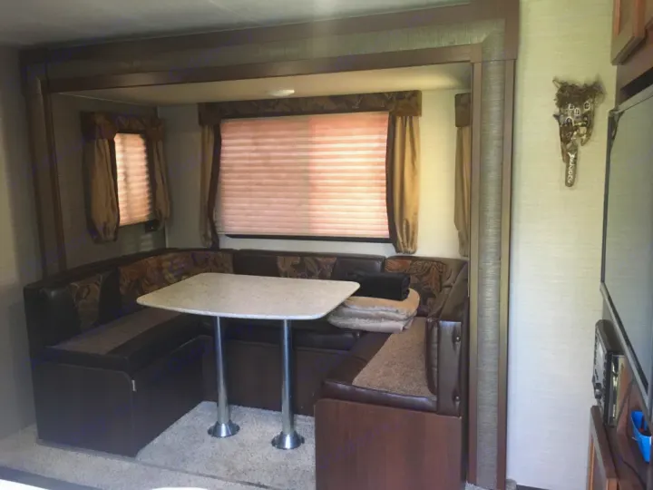 RV rental interior showing a U-shaped dining booth with a light table and window blinds. A cozy, functional space.. Keystone RV Bullet Ultra Lite 2016