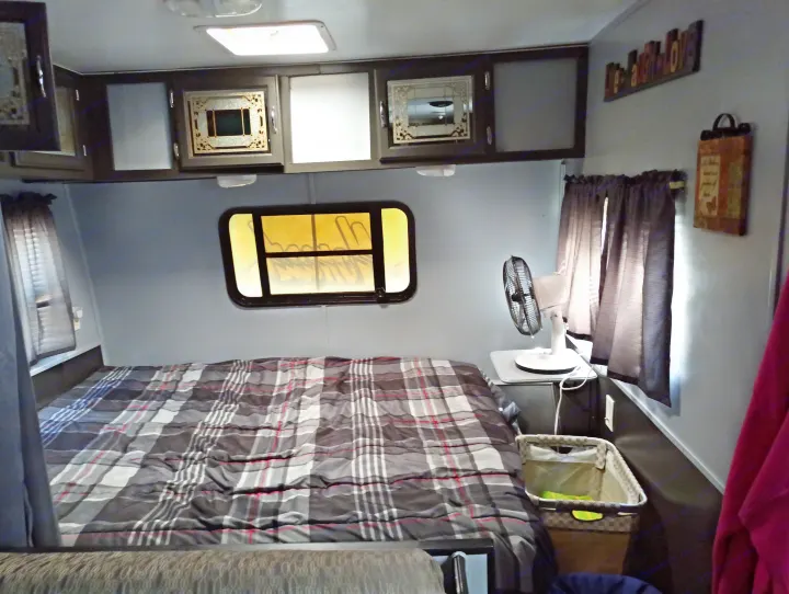 RV rental interior: a comfy plaid bed, overhead cabinets, window, and fan create a practical, cozy space for your travels.. Skyline Nomad 1996