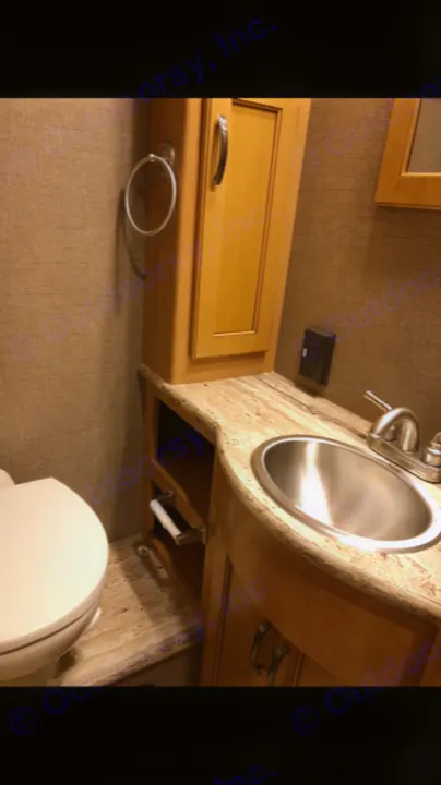 Inside an RV rental: a compact bathroom with a toilet on the left and a granite-topped vanity with a sink on the right.. Thor Motor Coach A.C.E 2017